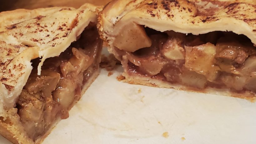 Apple pie cut open on a cutting board.