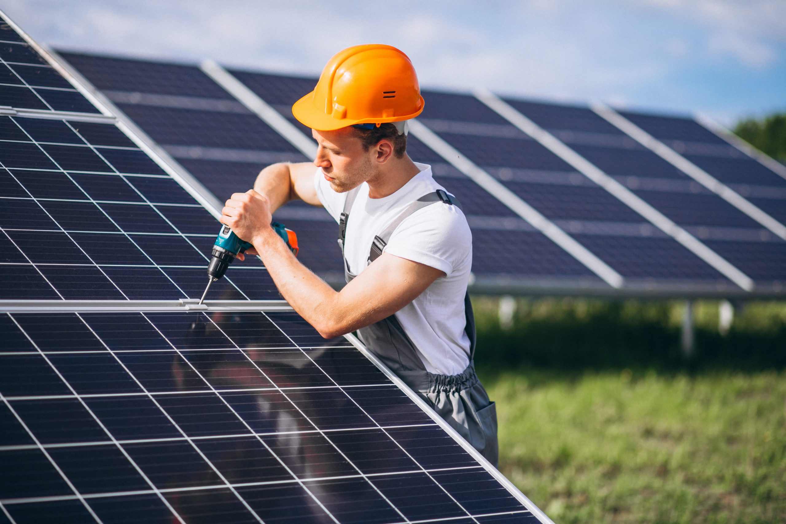 Worker installing solar panel with drill.